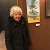 Marianne Krizner is shown standing next to her entry in the Spring exhibition